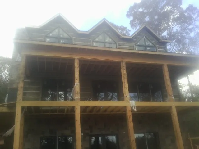 Dormers and porch framing on a large log home under construction — Roof Coating work by our crew in Ione