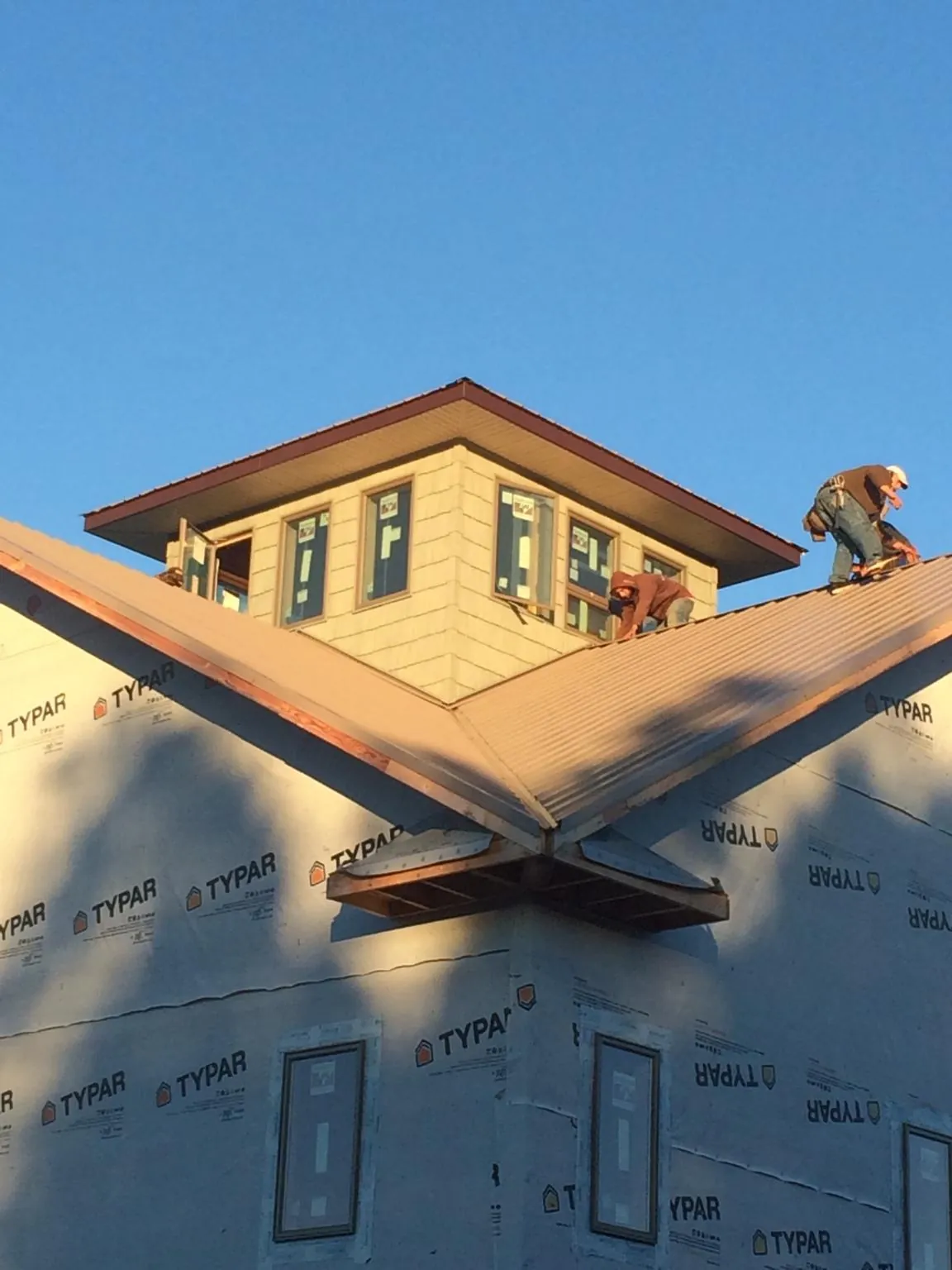 Roofers working around a rooftop cupola on a new metal roof at sunset — Roof Waterproofing in Ione by Roofing Brothers